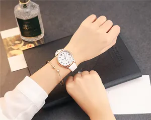 Close-up of minimalist women's watch with white leather strap and gold bead bracelet