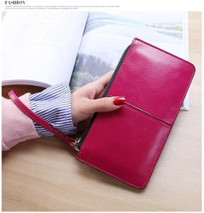 Detail of rose red shiny leather long wallet with zipper closure and wrist strap
