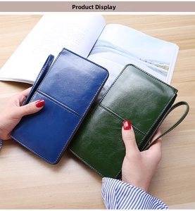 Detail view of deep blue and emerald green wax leather wristlet wallets on wood table
