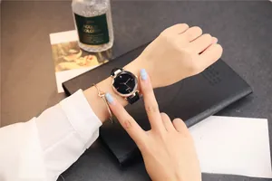 Détail d'une montre femme en or rose avec cadran noir facetté et bracelet en cuir