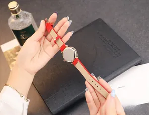 Détail d'une montre femme avec bracelet en cuir rouge et boîtier doré élégant