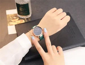 Montre à quartz pour femme avec bracelet en cuir vert et gourmette dorée sur un bureau