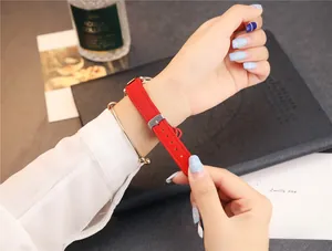 Gros plan d'un bracelet de montre en cuir rouge avec boucle argentée et bracelet jonc doré