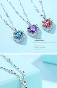 Dettagli artigianali di collane con cuore di cristallo blu, viola e rosa su catene d'argento