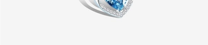 Dettaglio macro di un anello a cuore in argento con gemma blu e halo di diamanti