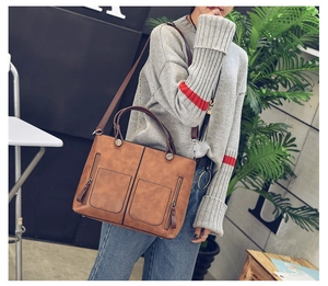 Brown vintage faux leather tote bag with front pockets and adjustable strap shown on model