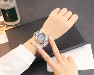 Close-up of rose gold watch with grey leather strap and minimalist gold cuff bracelet