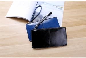 Detail view of glossy leather wristlet wallets in blue and black on a wooden desk
