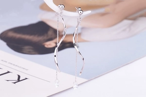 Detail of silver S-shaped wave tassel earrings with crystals and long hanging chains