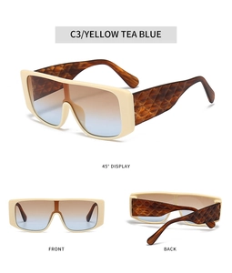 Detail view of beige oversized sunglasses with tortoiseshell temples and gradient lenses