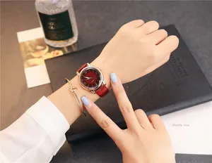 Close-up of burgundy leather quartz watch and gold knot bracelet on woman's wrist
