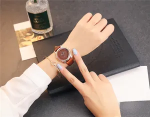 Detail of coffee leather watch with crocodile pattern paired with golden bangle