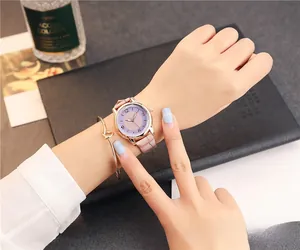 Close-up of a women's quartz watch with gradient dial paired with a gold knot bracelet