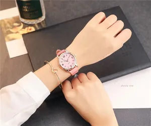 Close-up of a pink leather strap quartz watch with a minimalist gold knot bracelet