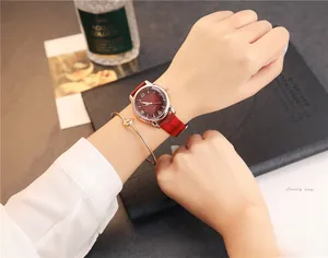 Detail of red leather watch with gold case and matching knot bracelet on a desk