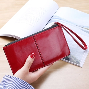 Long red leather zip wallet for women featuring a wrist strap and minimalist stitch detail