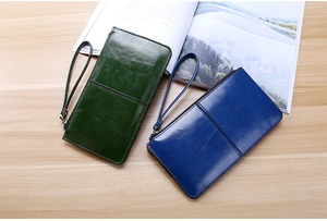Deep green and blue PU leather long zipper wallets with wristlets on a wooden table