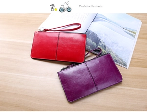 Detail view of red and purple long leather wallets with wristlets on a wooden desk