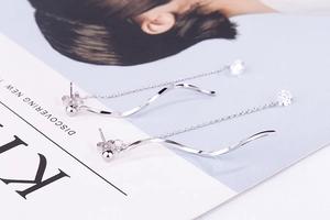 Macro view of silver S-shaped wave tassel earrings with sparkling cubic zirconia detail