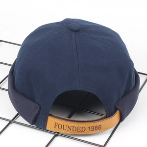 Détail de la patte de serrage en cuir et gravure 1986 sur le bonnet docker bleu marine