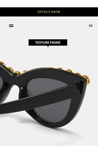 Close-up of black cat-eye sunglasses featuring intricate golden floral embossed details