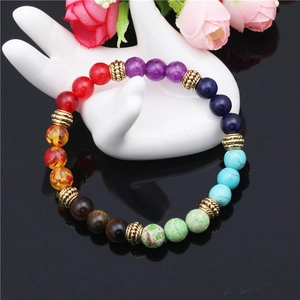 Chakra beaded energy bracelet with tiger eye and lapis lazuli on a white display hand