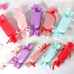 Overhead view of candy-shaped gift boxes with satin ribbons in various vibrant colors