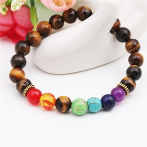 Tigerauge und Sieben Chakra Perlenarmband auf Handdisplay mit floralem Hintergrund