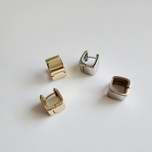 Detailed view of polished square huggie earrings in gold and silver finish on white background