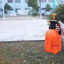 Outdoor handheld view of the manual pressure garden sprayer with orange body and black nozzle