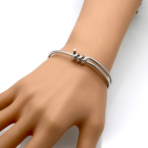 Close-up of a silver-toned woven knot bangle with minimalist industrial design on a model