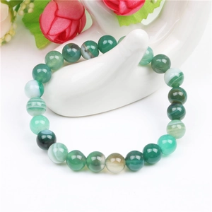 Detail of green agate elastic beaded bracelet displayed on a white hand model