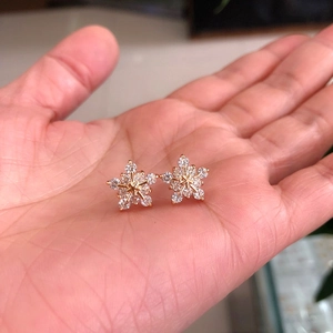 Close-up of snowflake earrings with AAA zircons on hand to show the actual product size