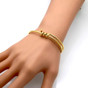 Detailed view of a gold knot cuff bracelet featuring a double-row woven open design