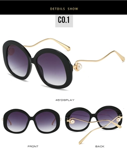 Detail view of trendy oval sunglasses with black frames and elegant pearl temple accents