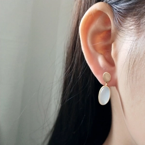Detail of 925 silver gold brushed earring with blue stone on female model ear