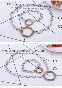 Detail of interlocking tricolor rings on a silver-toned oval chain necklace and bracelet
