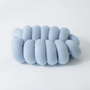 Detail of light blue knotted pillow showing soft knitted texture on white background