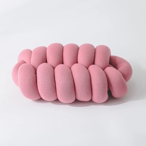 Close-up of pink woven knot pillow showing soft knit texture and creative decorative design