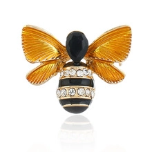 Detailed close-up of a bee brooch with golden wings and sparkling rhinestone stripes