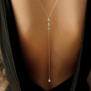 Close-up of golden leaf Y-necklace with three diamond accents on elegant model neck