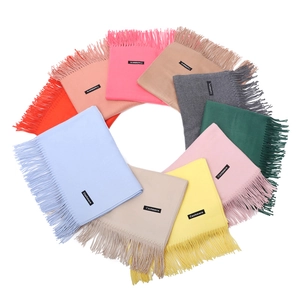 Detailed overhead view of assorted solid cashmere scarves with fringe and brand labels