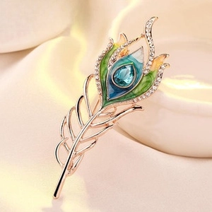 Macro shot of peacock feather brooch with blue enamel and sparkling crystal inlay