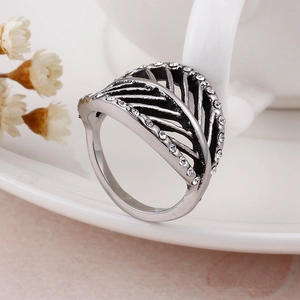 Retro titanium steel feather ring with white crystals on a white ceramic cup