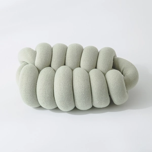 Close-up of the light green knitted knot pillow showing thick tubular texture and weave
