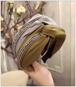 Détail de serre-tête large en tissu avec nœud croisé et accents de strass brillants