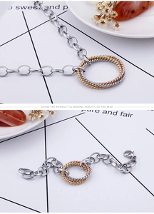 Macro detail of interlocking tricolor metal rings on chunky chain necklace and bracelet
