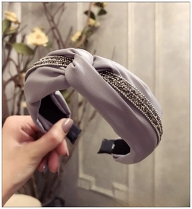 Détail d'un bandeau en tissu lilas torsadé avec strass brillants et design noué