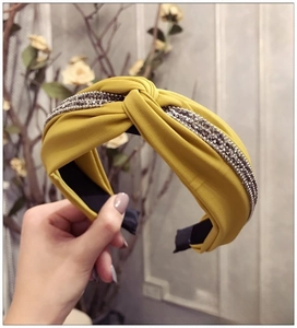 Détail du serre-tête noué jaune gingembre avec bordure en strass et texture de tissu