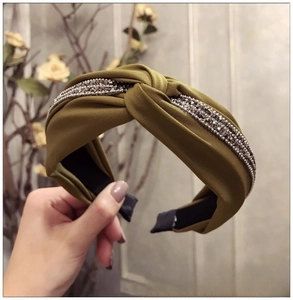 Détail du serre-tête en satin vert olive avec strass étincelants et large nœud torsadé